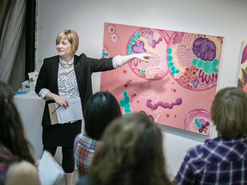 A professor points to a pink painting