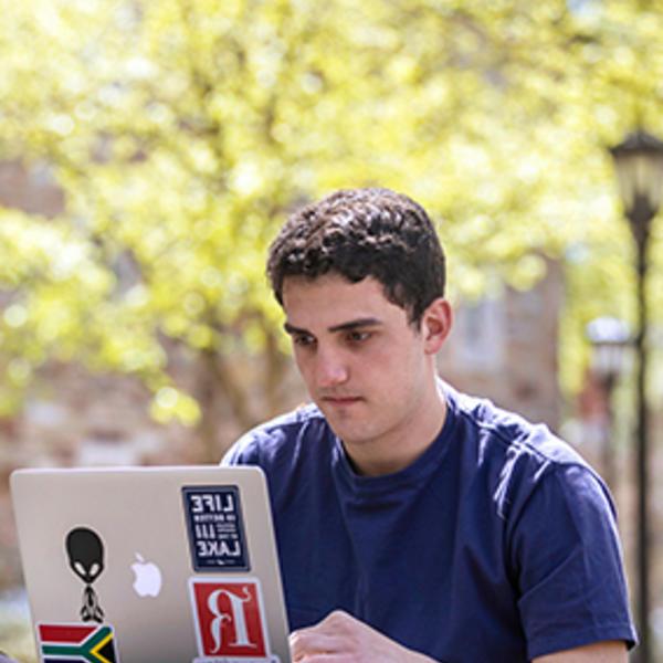 a young man studies a computer outside