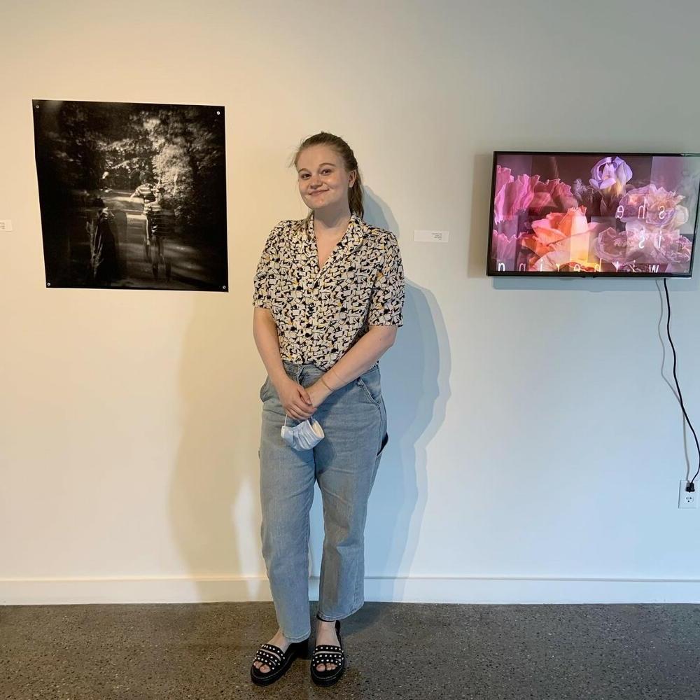 Emily Burkhead, '20, standing next to two of her pieces of art